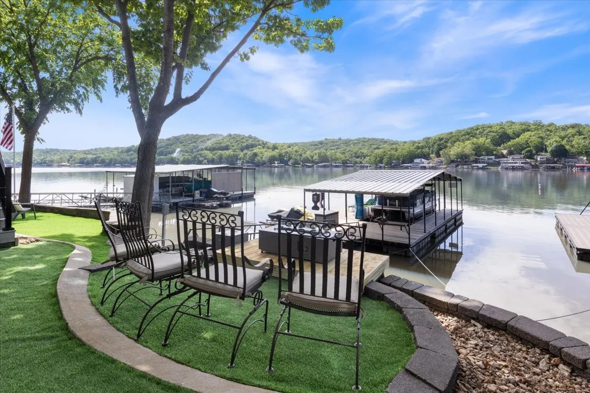 This image captures a peaceful outdoor seating area overlooking the lake, with a dock stretching out over the water. The scene includes lawn chairs set up for relaxation or socializing, and the expansive lake view in the background invites thoughts of unwinding, kayaking, or fishing.