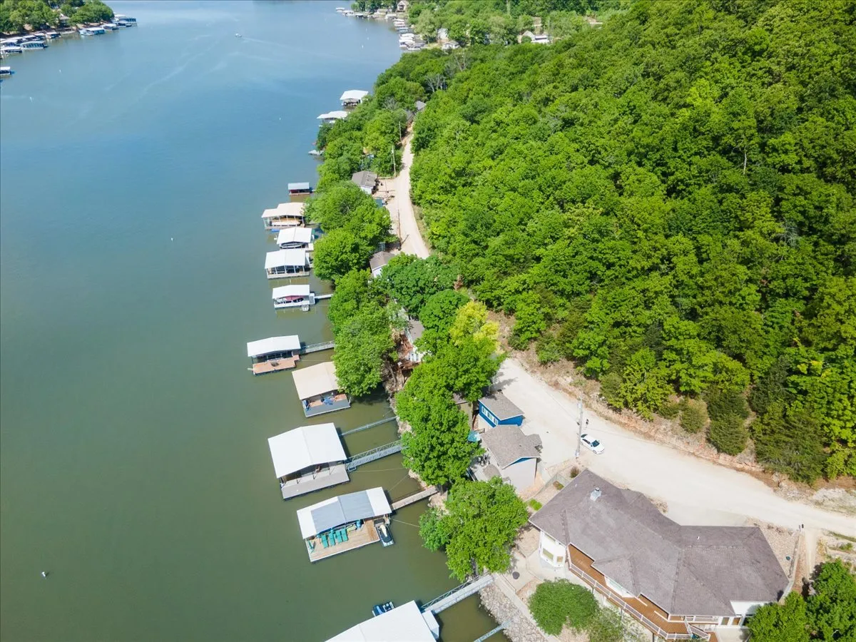 A wide exterior view capturing the lake, docks, and surrounding greenery. The scene offers a sense of tranquility while also showcasing opportunities for water activities such as boating, fishing, and swimming. A road is visible, suggesting easy access to nearby attractions.