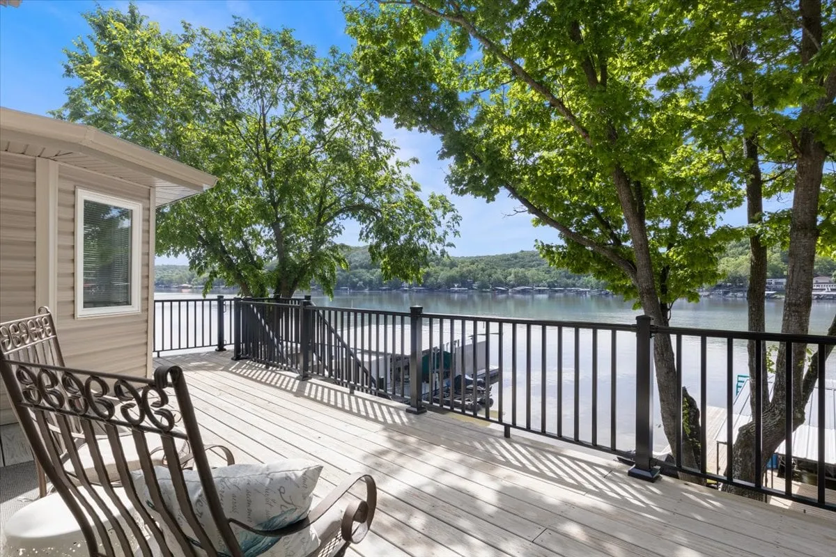 A spacious deck area surrounded by trees, offering unobstructed views of the lake. Comfortable seating is arranged to take advantage of the scenic perspective, creating an inviting space for morning coffee, focused work, or conversations in a natural setting.